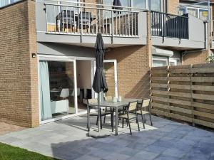 a table and chairs with an umbrella on a patio at Appartement op topligging! in Cadzand