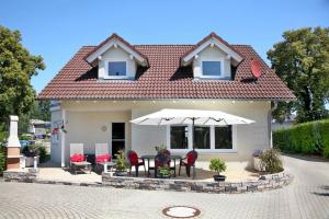 ein Haus mit einem Tisch, Stühlen und einem Sonnenschirm in der Unterkunft Ferienhaus Adler in Mirow in Mirow