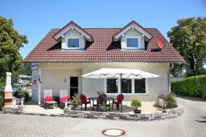 a house with a table and chairs and an umbrella at Ferienhaus Adler in Mirow in Mirow