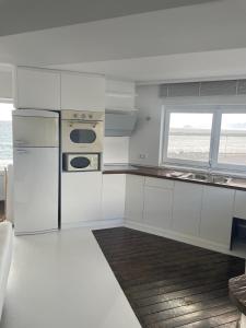 a white kitchen with a refrigerator and a window at Boathouse in Kardamaina