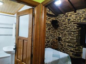 a bedroom with a stone wall with a bed and a sink at Casa Freixe Apartamentos Rurales in Santa Eulalia de Oscos