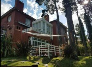 ein altes rotes Backsteinhaus mit einem weißen Balkon in der Unterkunft Dpto unico en un lugar magico en Pinamar ,Terrazas al Golf!! in Pinamar