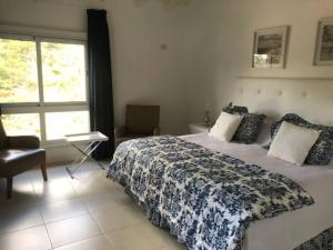 ein Schlafzimmer mit einem Bett und einem Stuhl und einem Fenster in der Unterkunft Dpto unico en un lugar magico en Pinamar ,Terrazas al Golf!! in Pinamar + 24 Fotos