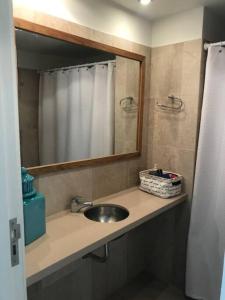 ein Waschbecken mit Spiegel und Duschvorhang in der Unterkunft Dpto unico en un lugar magico en Pinamar ,Terrazas al Golf!! in Pinamar