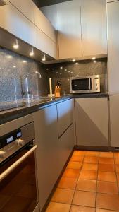 a kitchen with white cabinets and a microwave at Hameau des amandiers-vue mer & golf in Saint-Cyr-sur-Mer