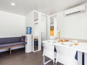 ein Wohnzimmer mit einem Kühlschrank, einem Tisch und Stühlen in der Unterkunft Mobile home Mediteran Superior by the pool in caravan park Strasko, Novalja in Novalja