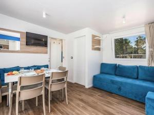 ein Wohnzimmer mit einem blauen Sofa und einem Tisch in der Unterkunft Mobile home Mediteran Superior by the pool in caravan park Strasko, Novalja in Novalja