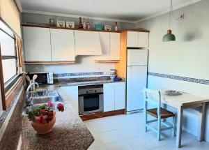 a kitchen with white cabinets and a sink and a table at Port Pollensa Pins 2 in Pollença