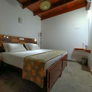 Schlafzimmer mit einem großen Bett mit einem Kopfteil aus Holz in der Unterkunft Zee Golf Affordable Luxury in Galle