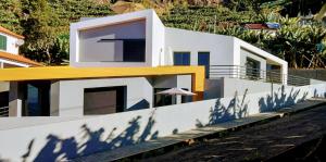 Biały dom z żółtym dachem i jego cieniem w obiekcie Anjos's Choice w mieście Ponta do Sol