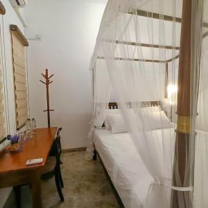 Schlafzimmer mit einem Bett und einem Holztisch in der Unterkunft Zee Golf Affordable Luxury in Galle
