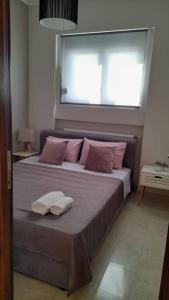 a bedroom with a bed with pink pillows and a window at Sunrise Apartment in Souda