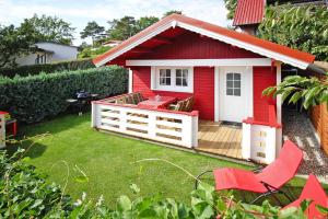 a red house with a deck and chairs in a yard at Holiday home, Plau am See in Plau am See