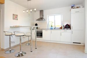 a kitchen with white cabinets and a counter with stools at Holiday home Barbara, Zarrentin in Zarrentin
