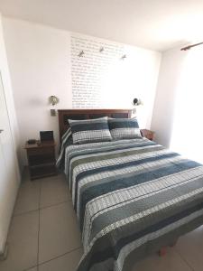 1 dormitorio con 1 cama grande con manta a rayas en Matiz 01, en Iquique