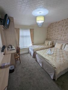 a hotel room with two beds and a television at The Stafford in Blackpool