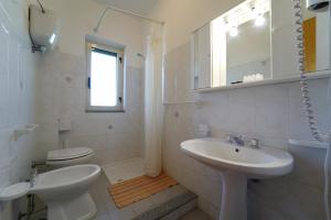 La salle de bains blanche est pourvue d'un lavabo et de toilettes. dans l'établissement Europa rooms and restaurant, à Capo Vaticano