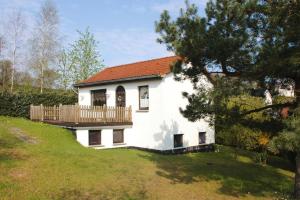 a white house with a deck on a hill at Cottage, Dolgen am See in Klein Sprenz