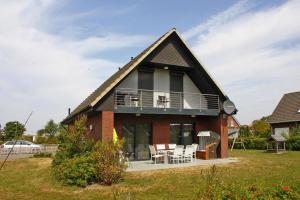 a house with a balcony and a table and chairs at Komfortables Ferienhaus in Friedrichskoog-Spitze in Friedrichskoog-Spitz