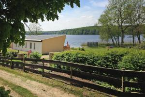 a house with a fence next to a lake at Double bungalow at the Groß Labenzer See, Klein Labenz in Klein Labenz