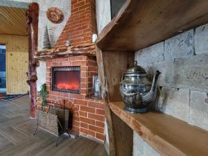 a brick fireplace with a tea kettle on a shelf at CASUTA CU SINDRILA in Dragoslavele