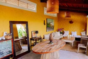 a living room with a table and a yellow wall at Qavi - Villa Robb em São Miguel do Gostoso in São Miguel do Gostoso