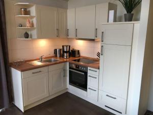 a kitchen with white cabinets and a sink and a refrigerator at Ferienhaus Müritzhus an der Müritz in Marienfelde
