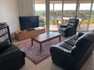 ein Wohnzimmer mit einem Sofa, einem TV und einem Tisch in der Unterkunft Vivonne Bay Island Getaway in Vivonne Bay