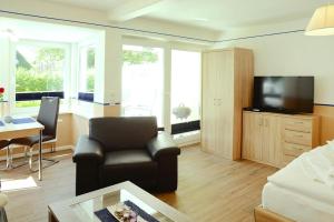 ein Wohnzimmer mit einem Sofa, einem Stuhl und einem TV in der Unterkunft Apartments home Wyk auf Föhr - DNS10067-SYA in Wyk auf Föhr