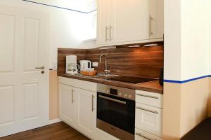 eine Küche mit weißen Schränken und einem Waschbecken in der Unterkunft Apartments home Wyk auf Föhr - DNS10067-SYA in Wyk auf Föhr