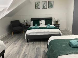 a bedroom with two beds and a chair at Home from home 2 bed executive style apartment in Bridgend