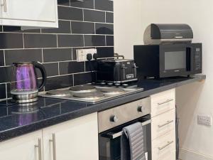 a kitchen with a microwave and a stove top oven at Comfortable and Modern 2-Bedroom Flat in Bridgend in Bridgend