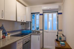 a kitchen with white cabinets and a sink and a window at Casas do Megué in Évora