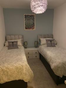 a bedroom with two beds and a chandelier at Custard creams cottage in Knaresborough