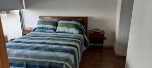 a bed with a blue and green comforter in a room at Capital 01 in Iquique