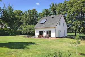 ein weißes Haus mit einem Sonnendach auf einem Feld in der Unterkunft Holiday home Kiebitz, Plau am See in Plau am See