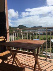 a wooden picnic table on a balcony with a view at marina sun 2 in Le Marin