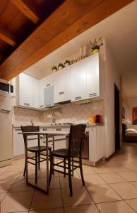 Sguardo a San Luca Apartment في بولونيا: مطبخ مع دواليب بيضاء وطاولة وكراسي