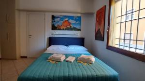 - une chambre avec un lit bleu et des serviettes dans l'établissement Sguardo a San Luca Apartment, à Bologne