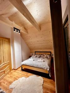 a bedroom with a bed in a wooden ceiling at Tatra Village in PyzÃ³wka