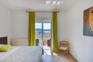 a bedroom with a bed and a window with green curtains at Apartments Juric in Rab +40 photos