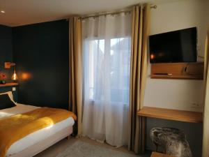 a bedroom with a bed and a window with a television at VILLA VOLTAIRE in Clamart