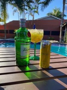 a green bottle and a glass sitting on a table at Casa com piscina em boraceia a 400 metros da praia in Boracéia
