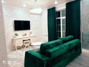 a living room with a green couch and a television at Large Green Apartment in Oral