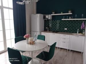 cocina con mesa blanca y sillas verdes en Green Apartment en Oral