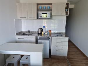 een witte keuken met een wastafel en een magnetron bij Aires de Capital Depto in Salta