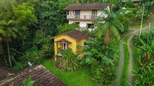 a small yellow house in the middle of a forest at Chales Sol Paraty in Paraty