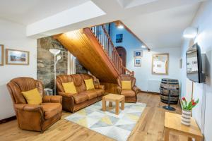 una sala de estar con muebles de cuero y una escalera. en Beautiful Character House in Muir of Ord en Muir of Ord