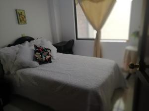 a bedroom with a white bed with a pillow on it at Habitaciones en Edificio Ginebra Manizales in La Linda