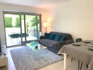ein Wohnzimmer mit einem Sofa und einem Tisch in der Unterkunft Rez-de-jardin - Résidence avec Piscine - Deauville in Deauville